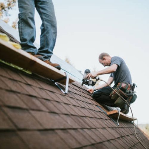 A roofer and crew work on putting in new roofing shingles.  Small local business serving local families in Washington State.