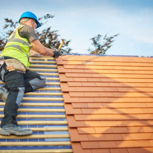 a roofer nails on the roof tiles
